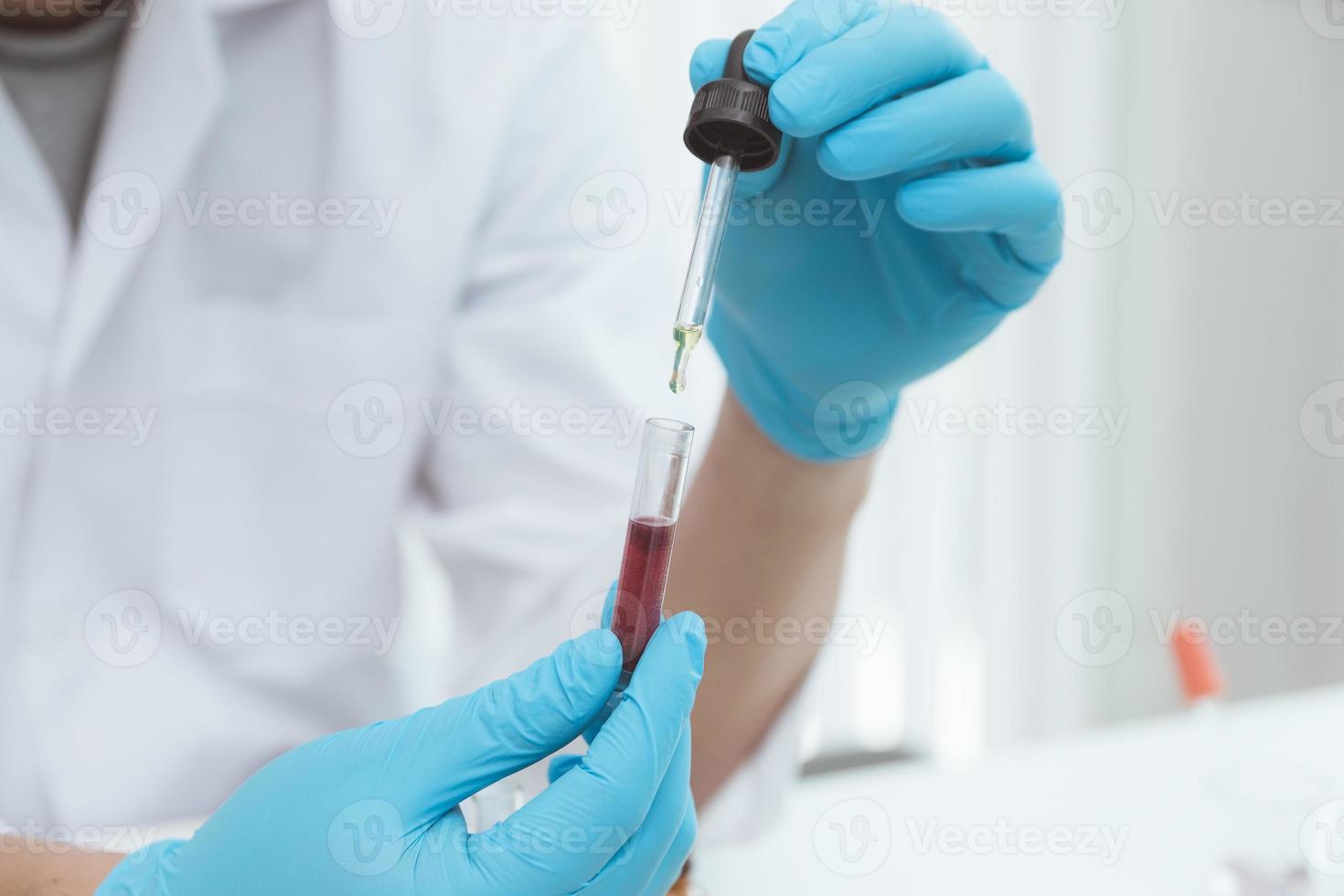 microbiologiste ou médecin scientifique portant des vêtements de protection contre les risques biologiques avec un tube d'échantillon biologique contaminé coronavirus covid 19 échantillon de sang infecté. photo