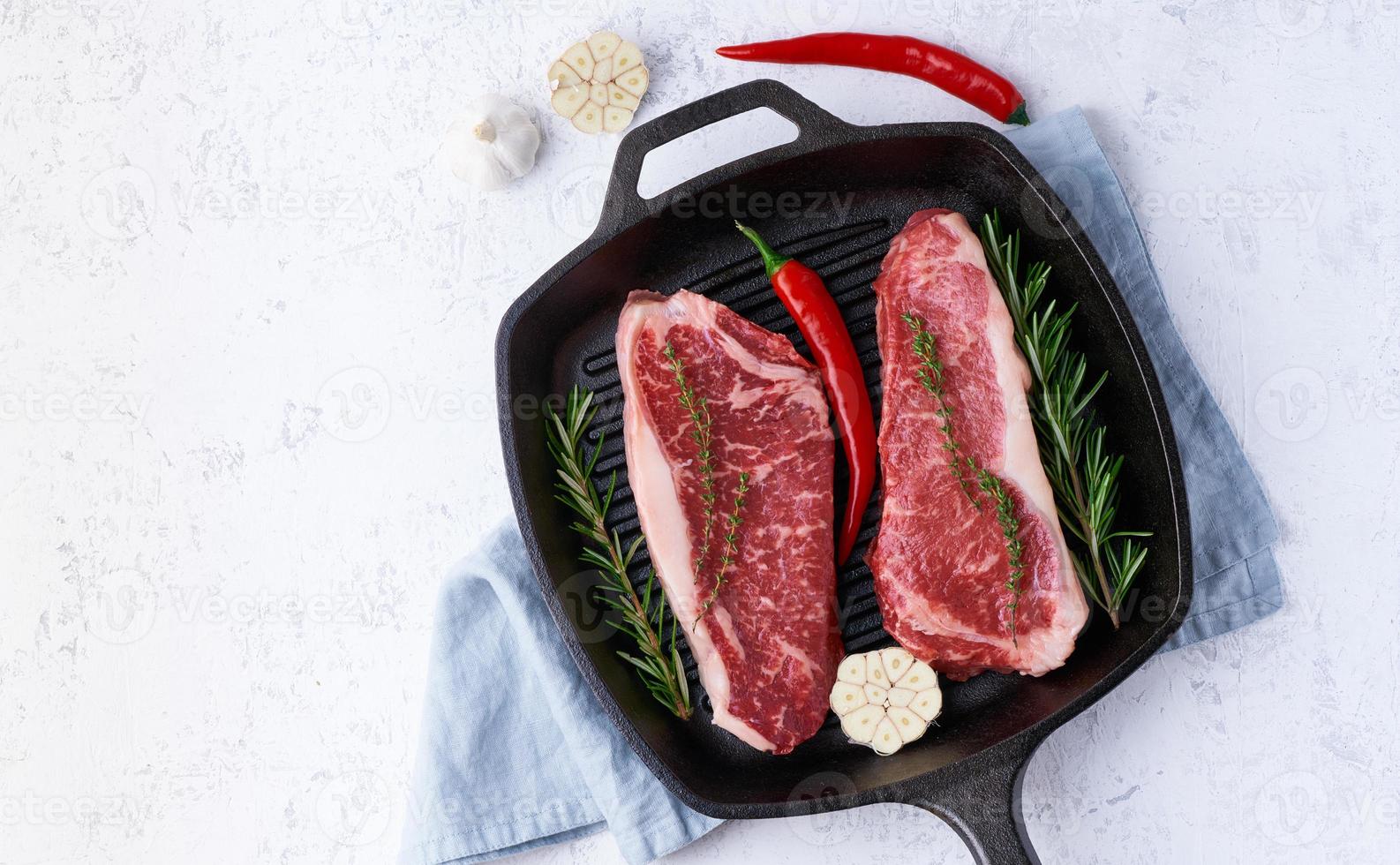 deux pièces de viande crue fraîche, filet de bœuf, contre-filet marbré dans une grande poêle en fonte. vue de dessus photo