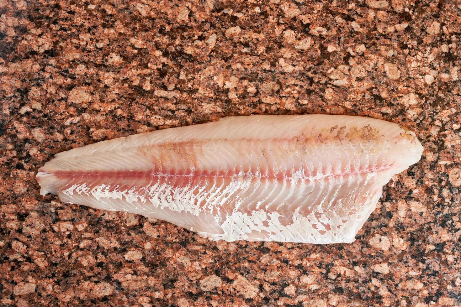 filet de poisson de sandre cru frais sur une table en marbre brun foncé. vue de dessus photo