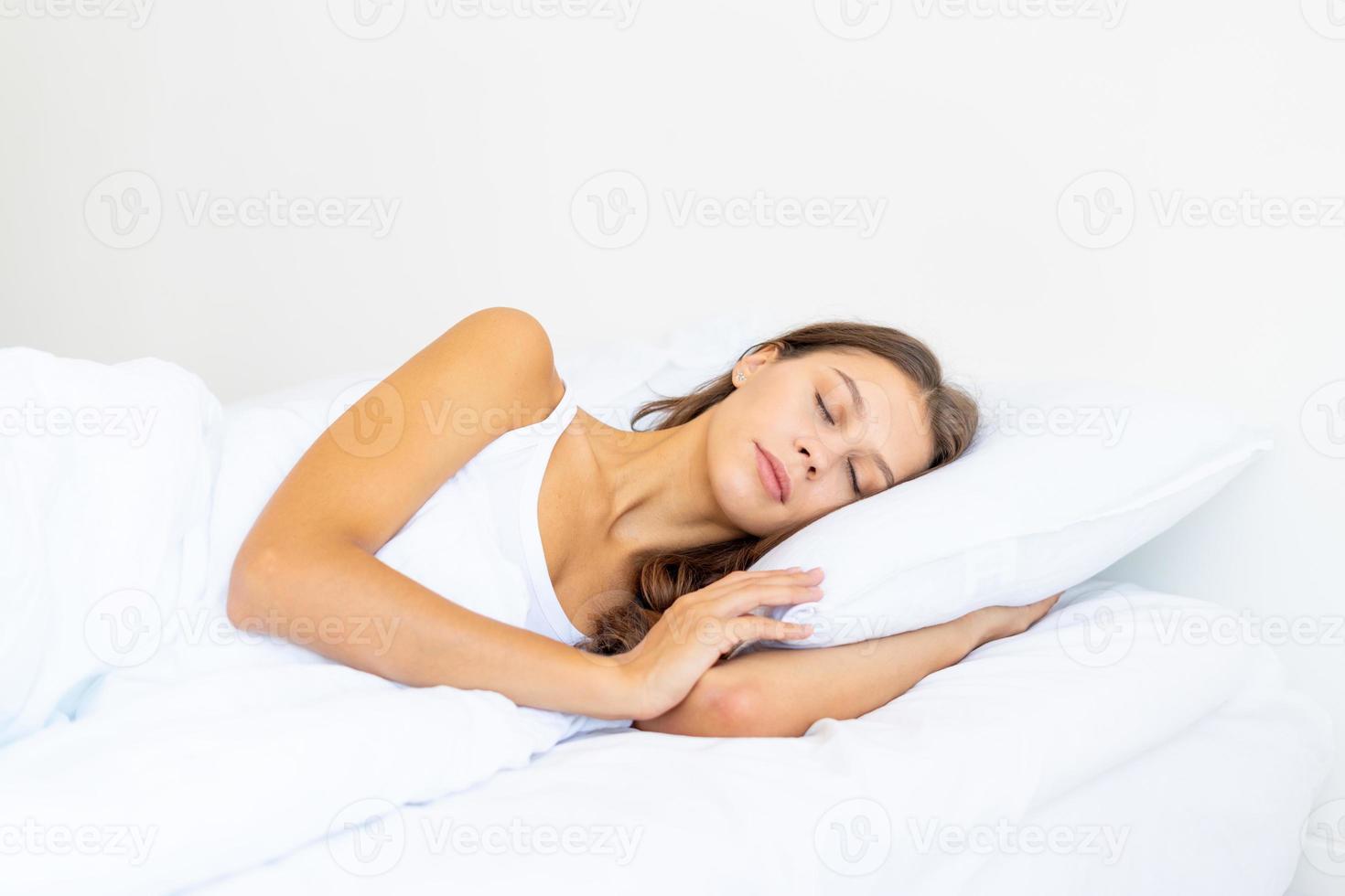 vue de côté portrait de taille d'une belle femme endormie dans son lit. femme aux cheveux longs au repos photo