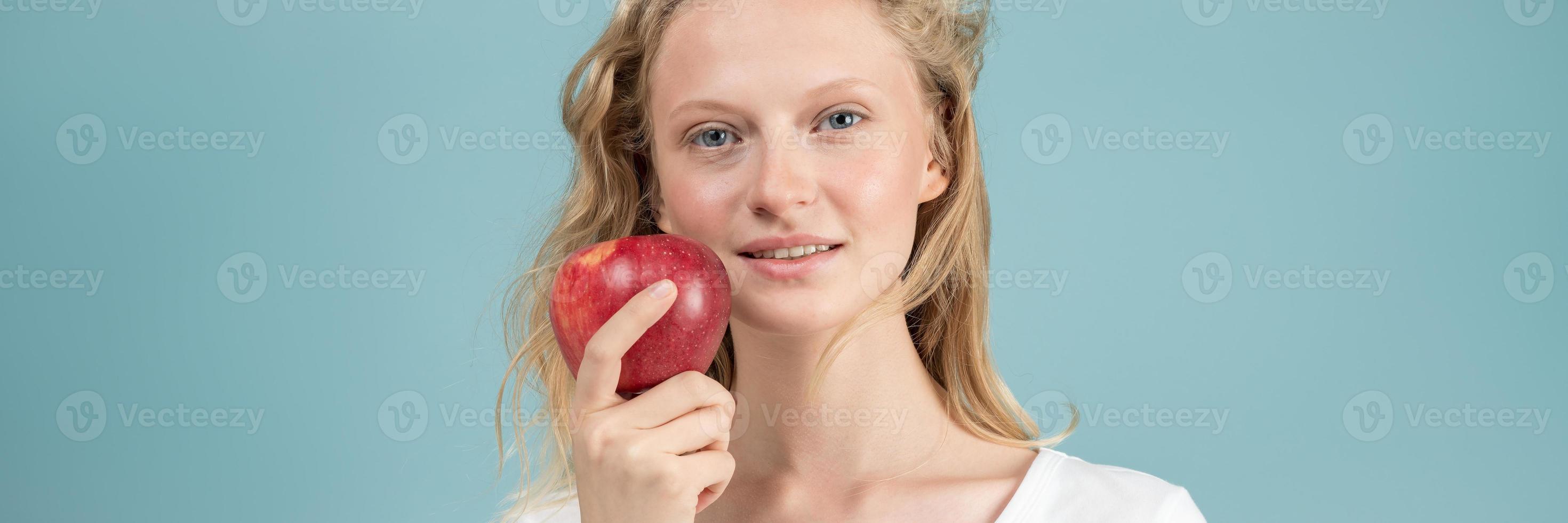 bannière longue largeur avec portrait de jeune femme souriante avec pomme rouge. visage frais photo