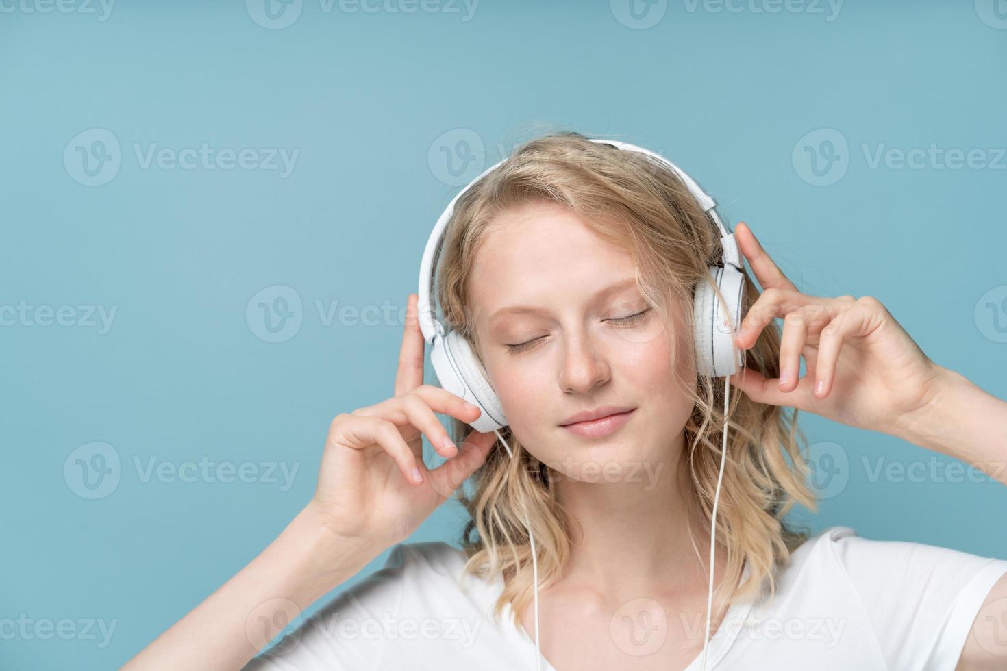 portrait en gros plan d'une jeune femme les yeux fermés écoutant de la musique via un casque photo