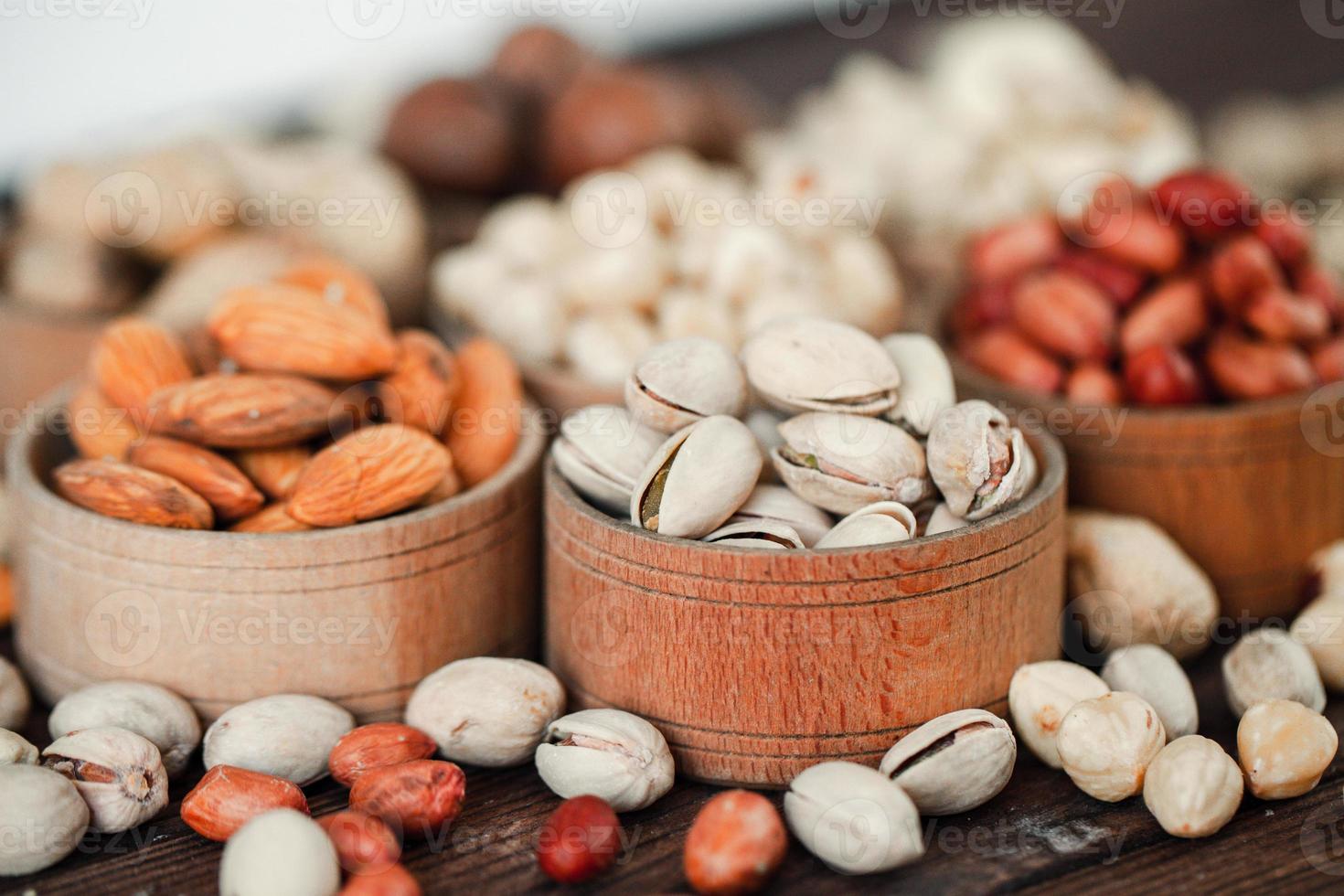 assortiment de noix pour un fond amande, noix, noix de cajou, pistaches, noisettes, cacahuètes, macadamia collection de différentes variétés de noix. composition avec des aliments sains de fruits secs. biologique. photo