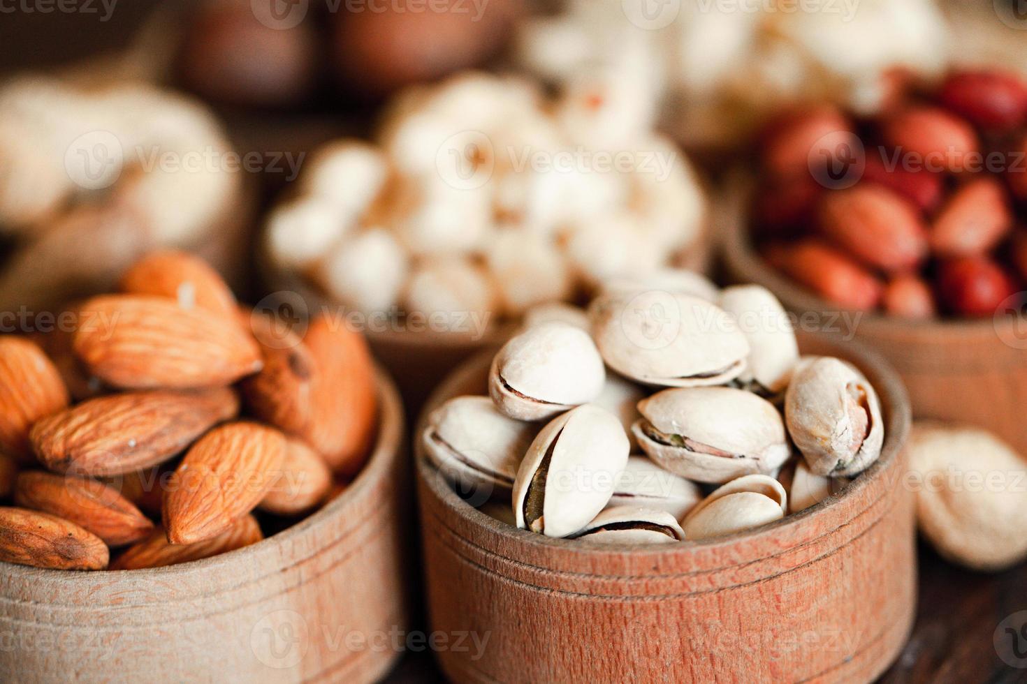 assortiment de noix pour un fond amande, noix, noix de cajou, pistaches, noisettes, cacahuètes, macadamia collection de différentes variétés de noix. composition avec des aliments sains de fruits secs. biologique. photo