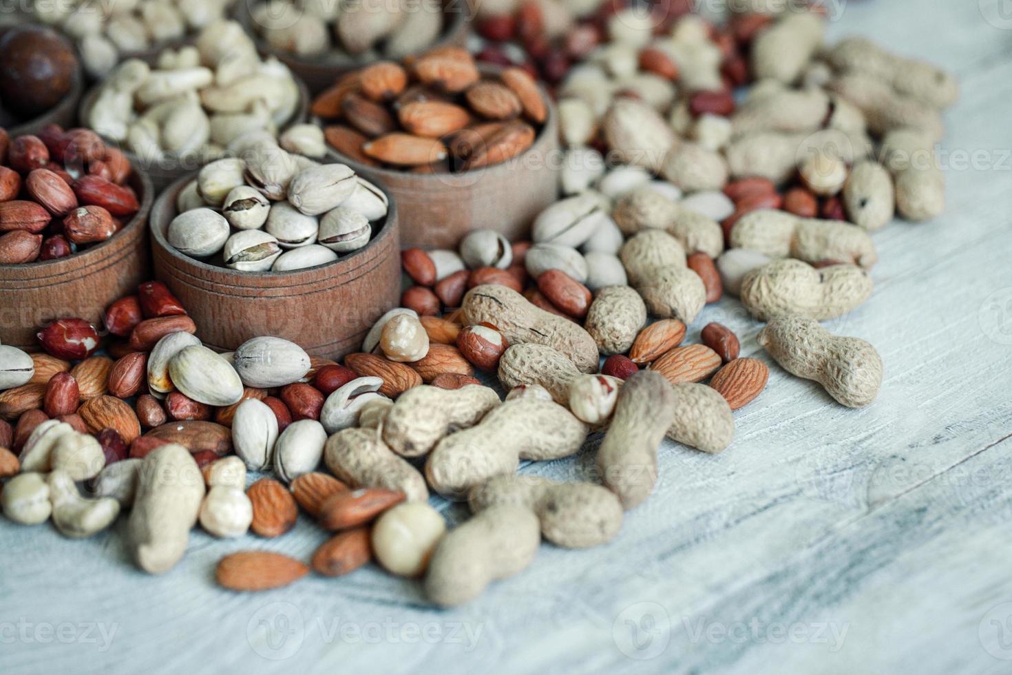 assortiment de noix pour un fond amande, noix, noix de cajou, pistaches, noisettes, cacahuètes, macadamia collection de différentes variétés de noix. composition avec des aliments sains de fruits secs. biologique. photo