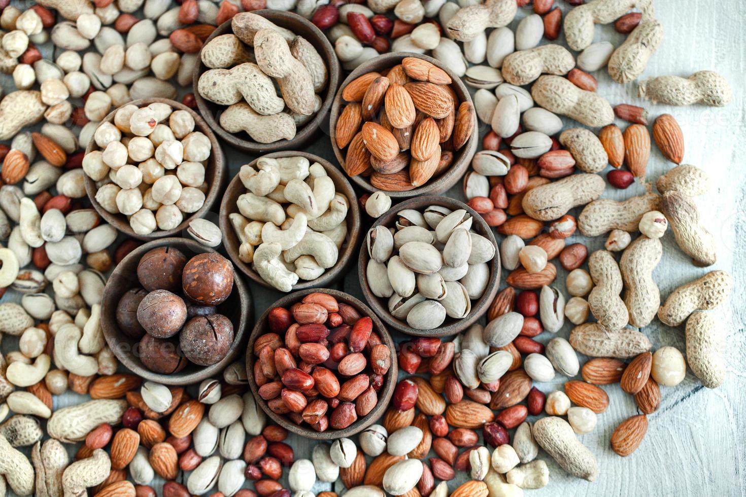 assortiment de noix pour un fond amande, noix, noix de cajou, pistaches, noisettes, cacahuètes, macadamia collection de différentes variétés de noix. composition avec des aliments sains de fruits secs. biologique. photo