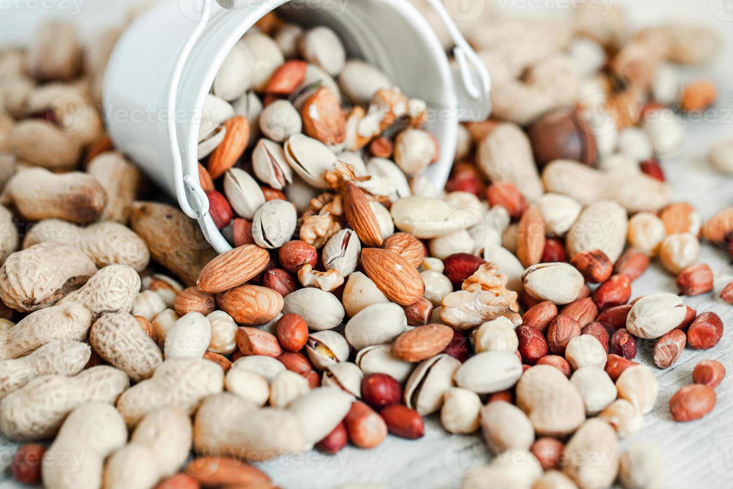 assortiment de noix pour un fond amande, noix, noix de cajou, pistaches, noisettes, cacahuètes, macadamia collection de différentes variétés de noix. composition avec des aliments sains de fruits secs. biologique. photo