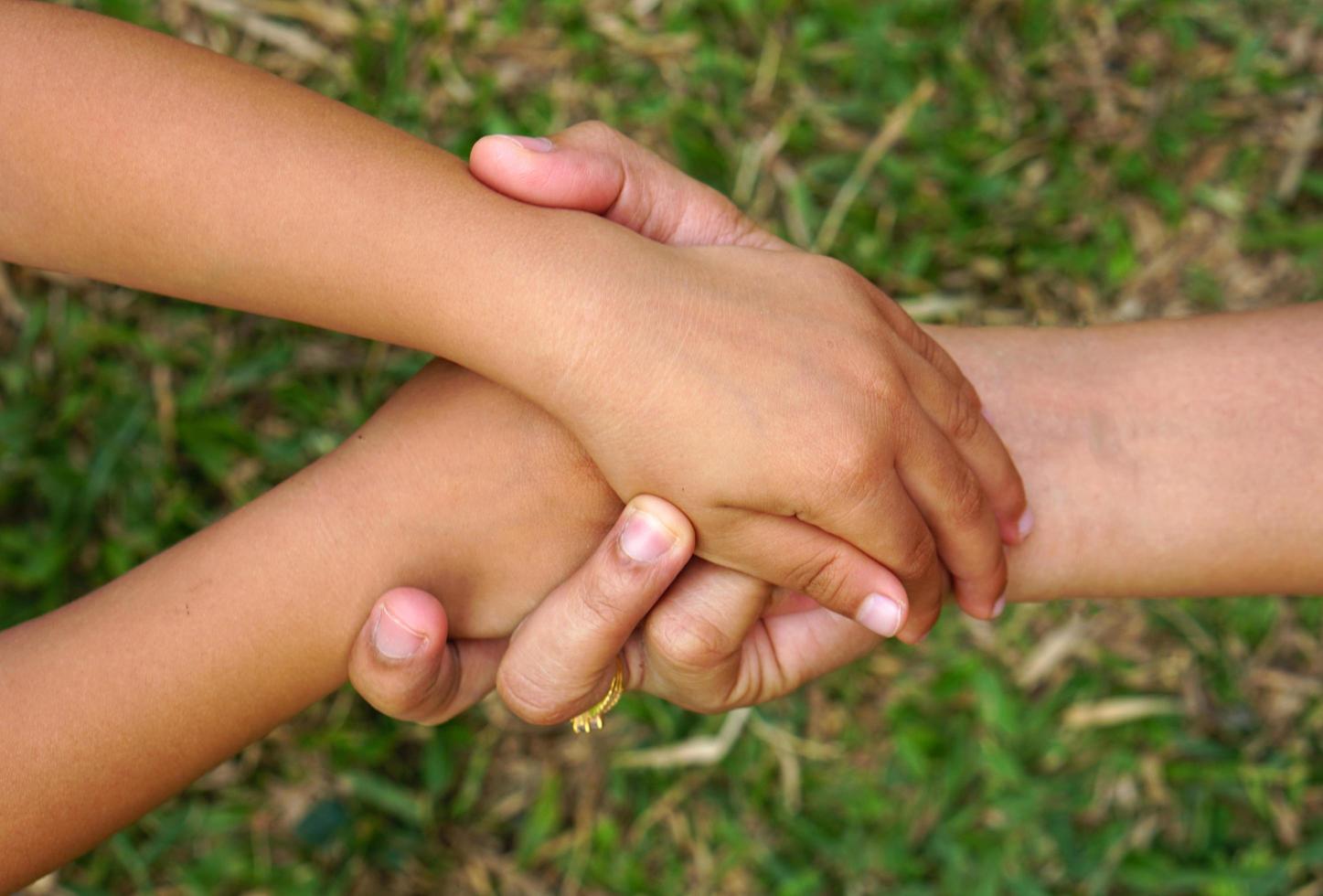 main de la mère tenant la main d'une petite fille sur fond bokeh. concept d'amour et de famille. photo