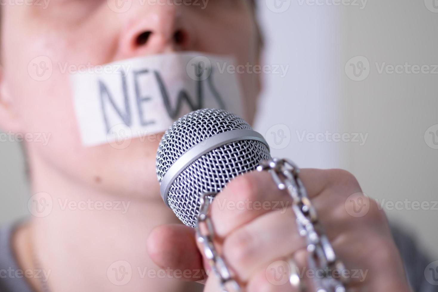 un homme bâillonne sa bouche avec du ruban adhésif en disant des nouvelles en essayant de parler dans un microphone. photo