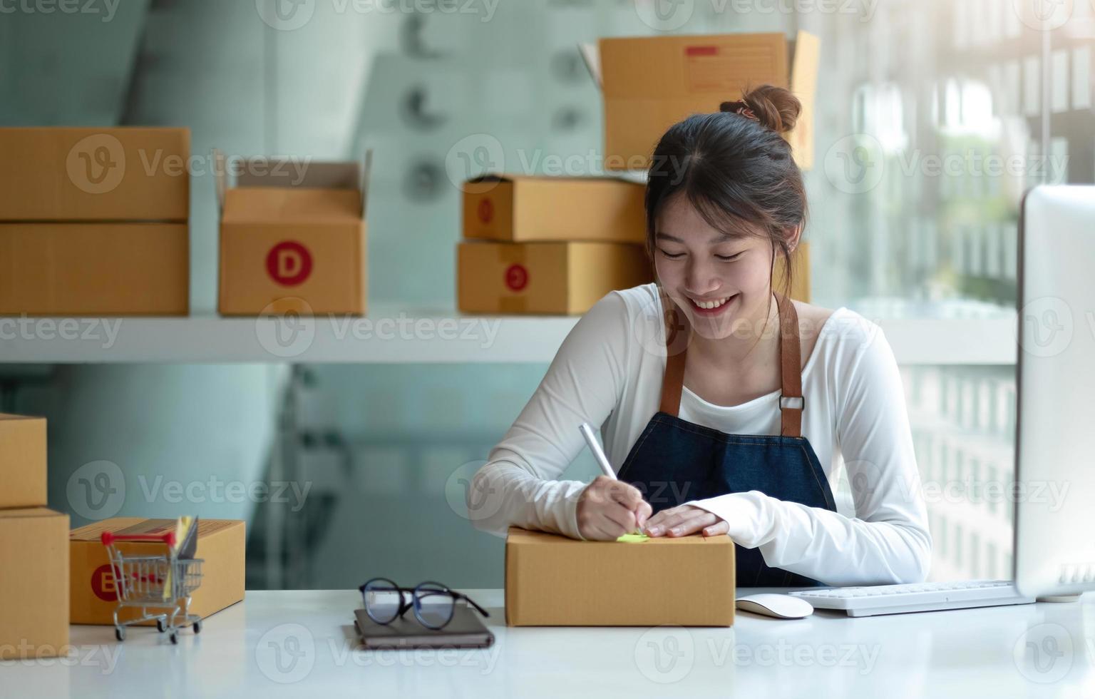 entrepreneur de petite entreprise asiatique PME écrivant l'adresse sur une boîte en carton sur le lieu de travail entrepreneur de petite entreprise PME, travaillant avec une boîte à la maison. photo