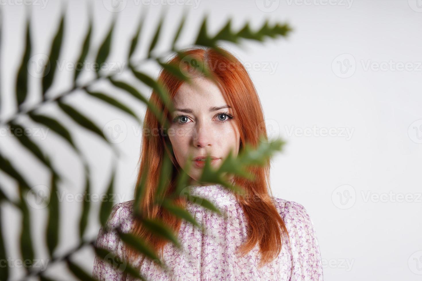 Mid adult woman se cachant derrière les feuilles de palmier des plantes d'intérieur photo