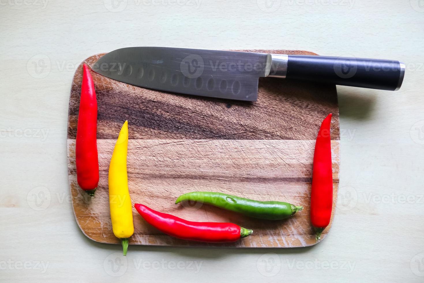 vue de dessus et en perspective du piment et du couteau en acier sur une planche à découper en bois avec un arrière-plan isolé photo