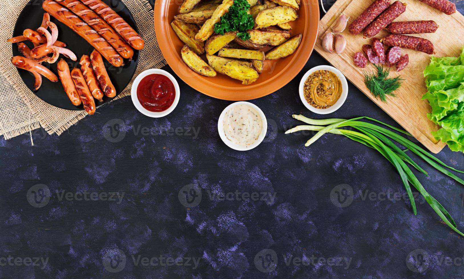 quartiers de pommes de terre au four avec saucisses et épices. vue de dessus photo