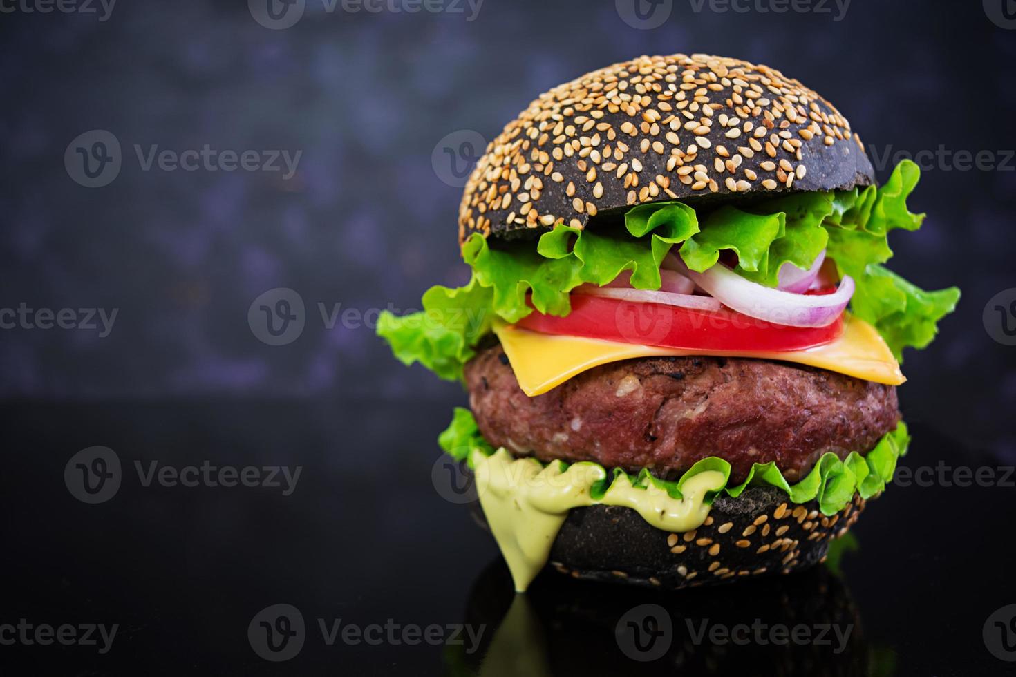 burger fait à la main sur fond sombre. délicieux burger noir photo