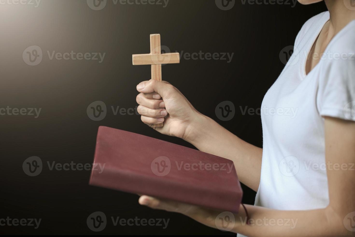 mains tenant une croix en bois sur la sainte bible russe ouverte sur fond de lever de soleil, crucifix, symbole de la foi. photo