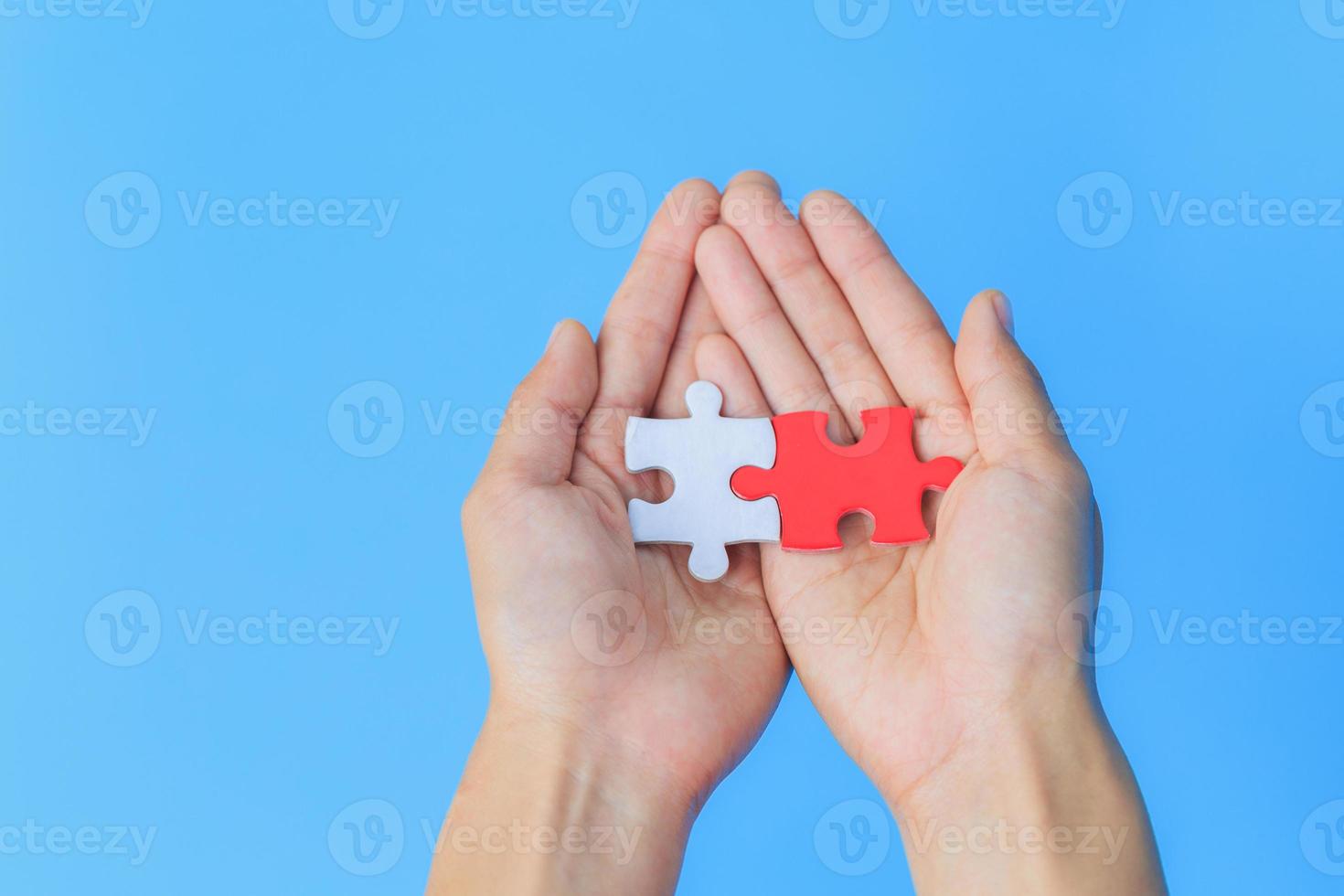 puzzles blancs et rouges. mis main dans la main ensemble. fond bleu. la notion de coopération. investissement commun. coopération pour réussir. travail en équipe. photo