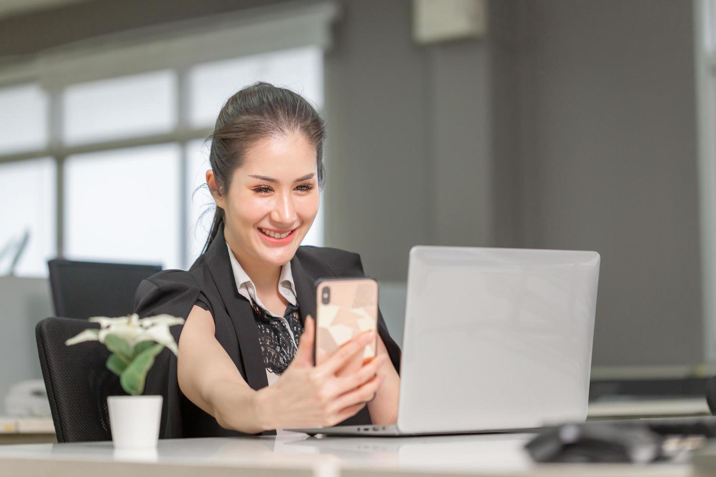 joyeuse femme d'affaires utilisant le téléphone au bureau. jolie fille excitée utilisant un smartphone au bureau, femme travaillant dans son bureau à domicile photo