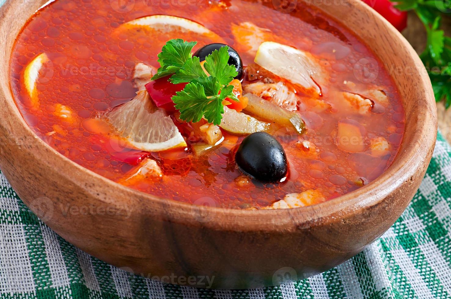 soupe solyanka russe avec viande, olives et cornichons dans un bol en bois photo