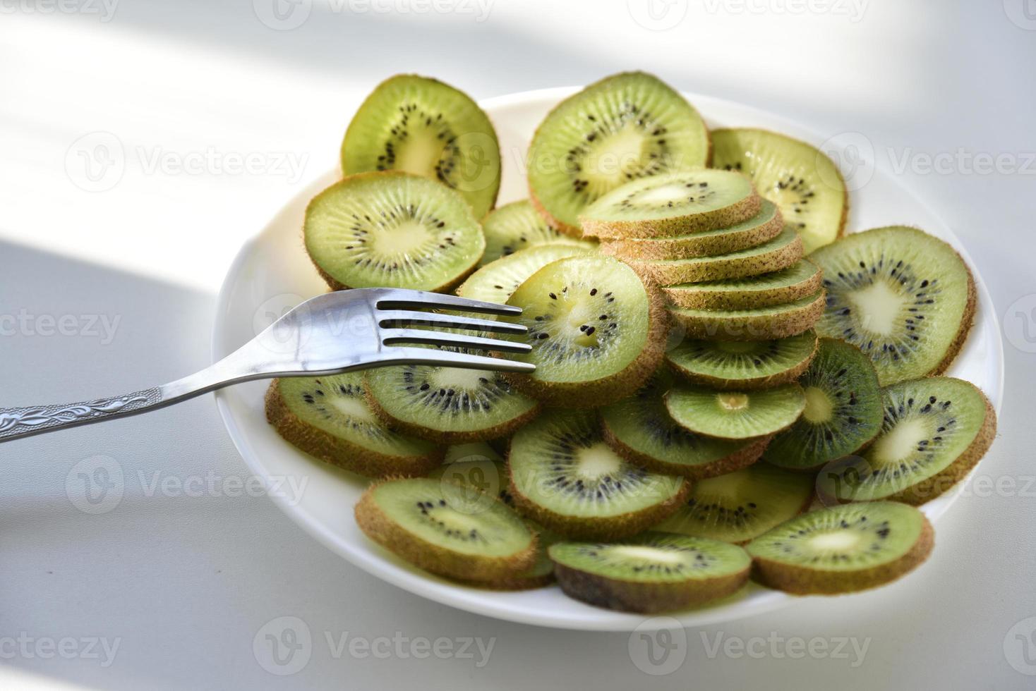 tranches de kiwi sur une plaque blanche avec une fourchette photo