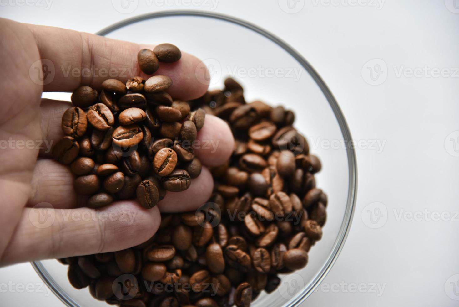 Grains de café dans un bol en verre sur fond blanc photo