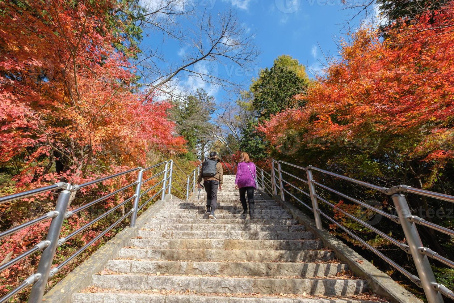 quelques touristes marchent jusqu'au sentier escarpé avec de l'érable vibrant en automne photo