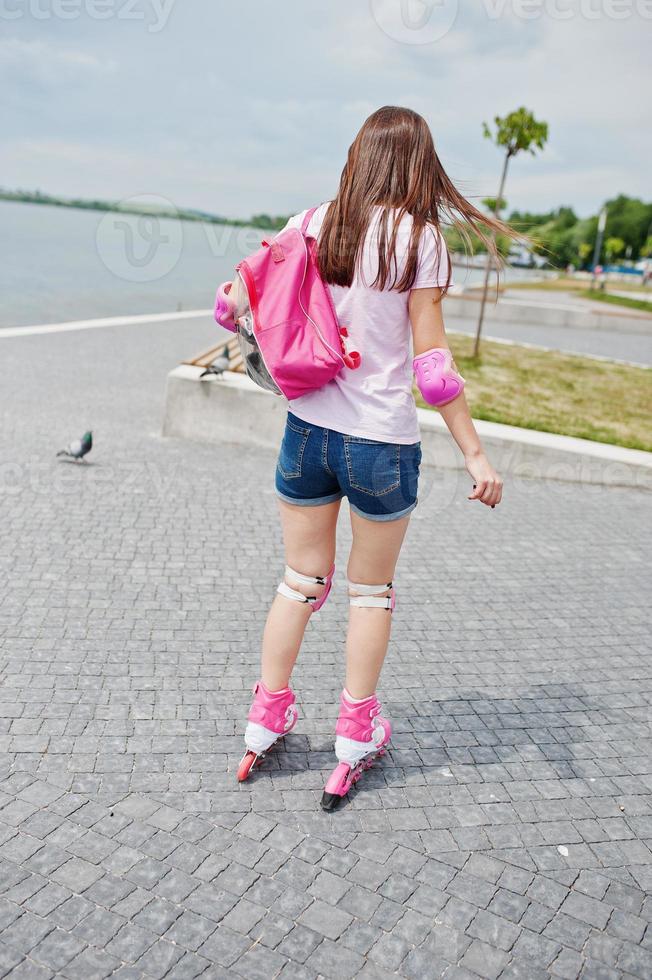 portrait d'une belle jeune femme en vêtements décontractés faisant du patin à roues alignées sur le trottoir dans le parc. photo