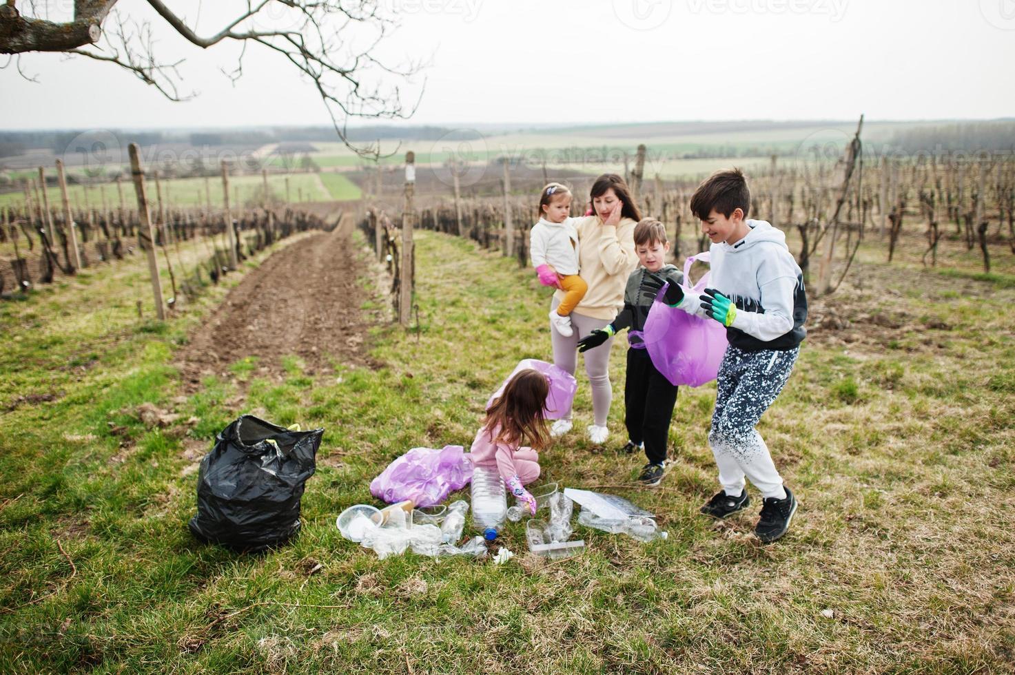 famille avec sac poubelle ramassant les ordures pendant le nettoyage dans les vignes. conservation de l'environnement et écologie, recyclage. photo
