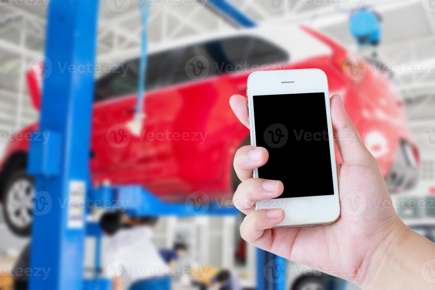 Main de femme tenir un téléphone intelligent mobile à écran tactile avec un centre d'entretien de garage de voiture photo