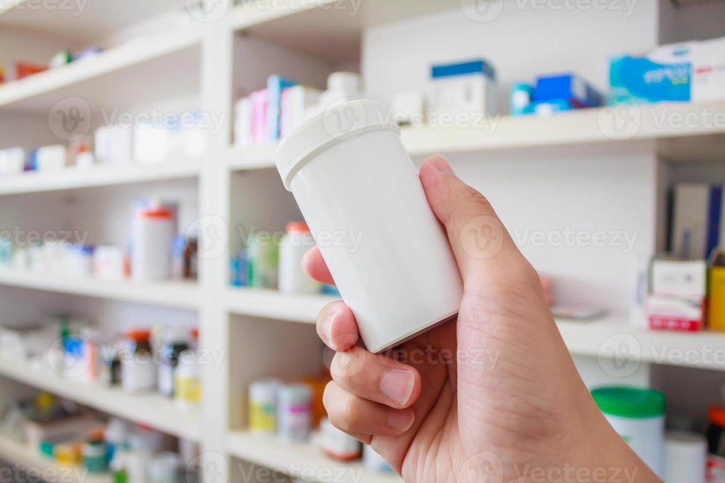 Main tenir le flacon de médicament dans la pharmacie photo