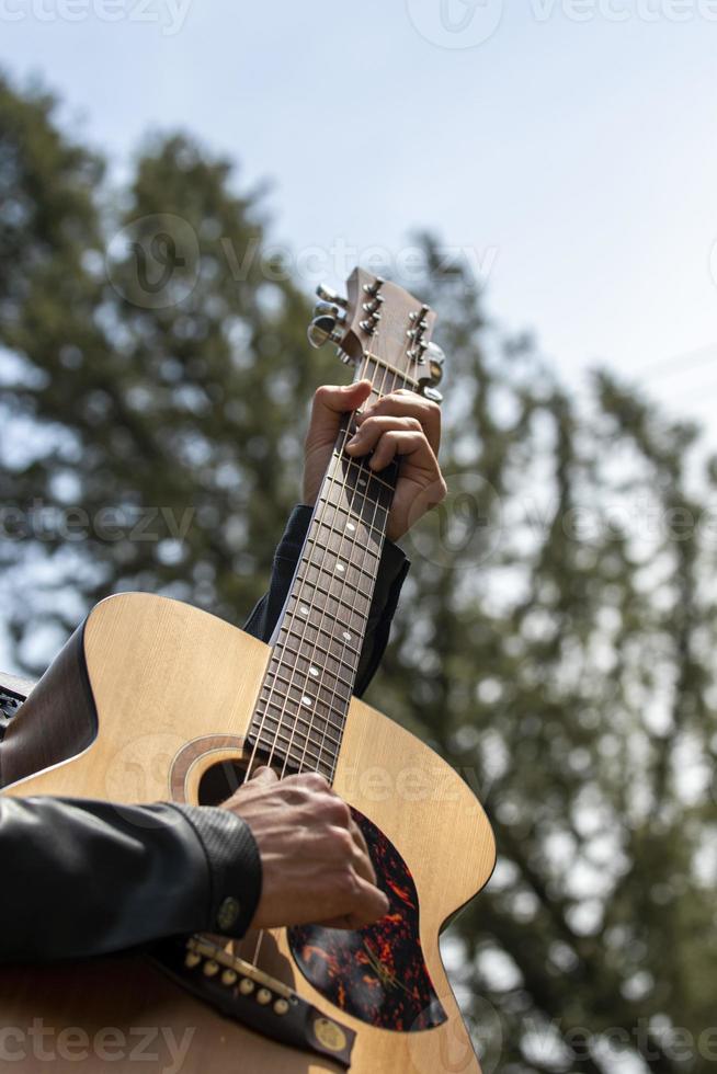 les mains jouent de la guitare à l'extérieur pendant la journée photo