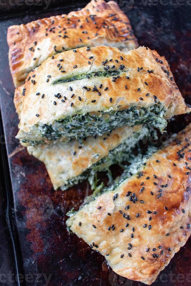 pâte feuilletée aux épinards tranchés et au fromage avec graines de sésame noir photo