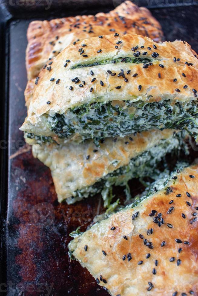 pâte feuilletée aux épinards tranchés et au fromage avec graines de sésame noir photo