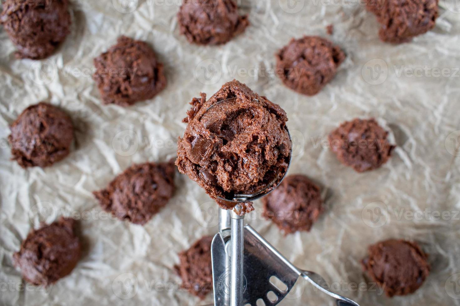 Évider la pâte à biscuits aux pépites de chocolat sur une plaque à biscuits en papier ciré mise à plat photo