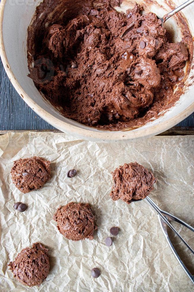 Évider la pâte à biscuits aux pépites de chocolat sur une plaque à biscuits en papier ciré mise à plat photo