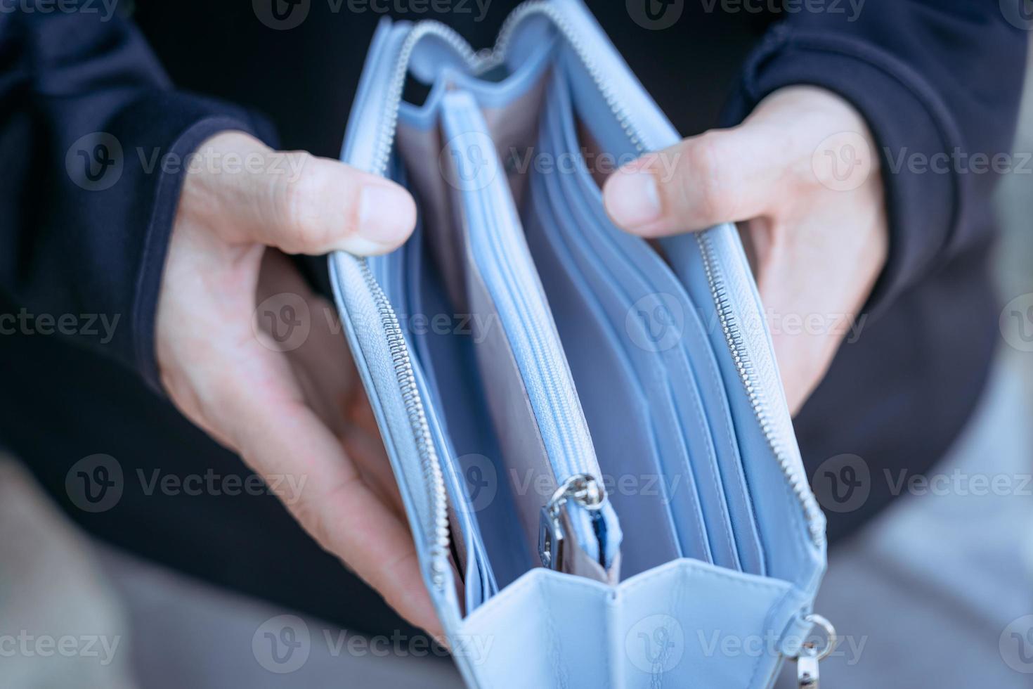 gros plan sur un portefeuille vide bleu à la main en raison des effets du chômage. photo