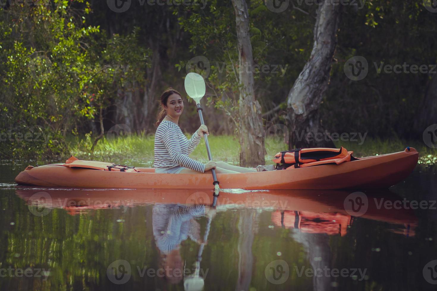 Une jeune femme asiatique naviguant en kayak de mer dans le lagon de fleurs de lotus avec bonheur photo