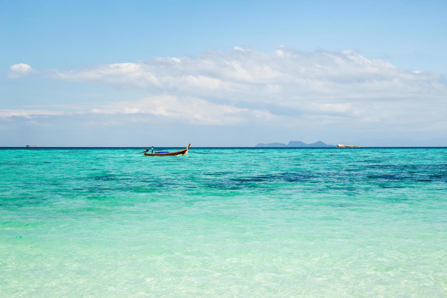 mer turquoise avec bateau à longue queue sur une île tropicale. photo