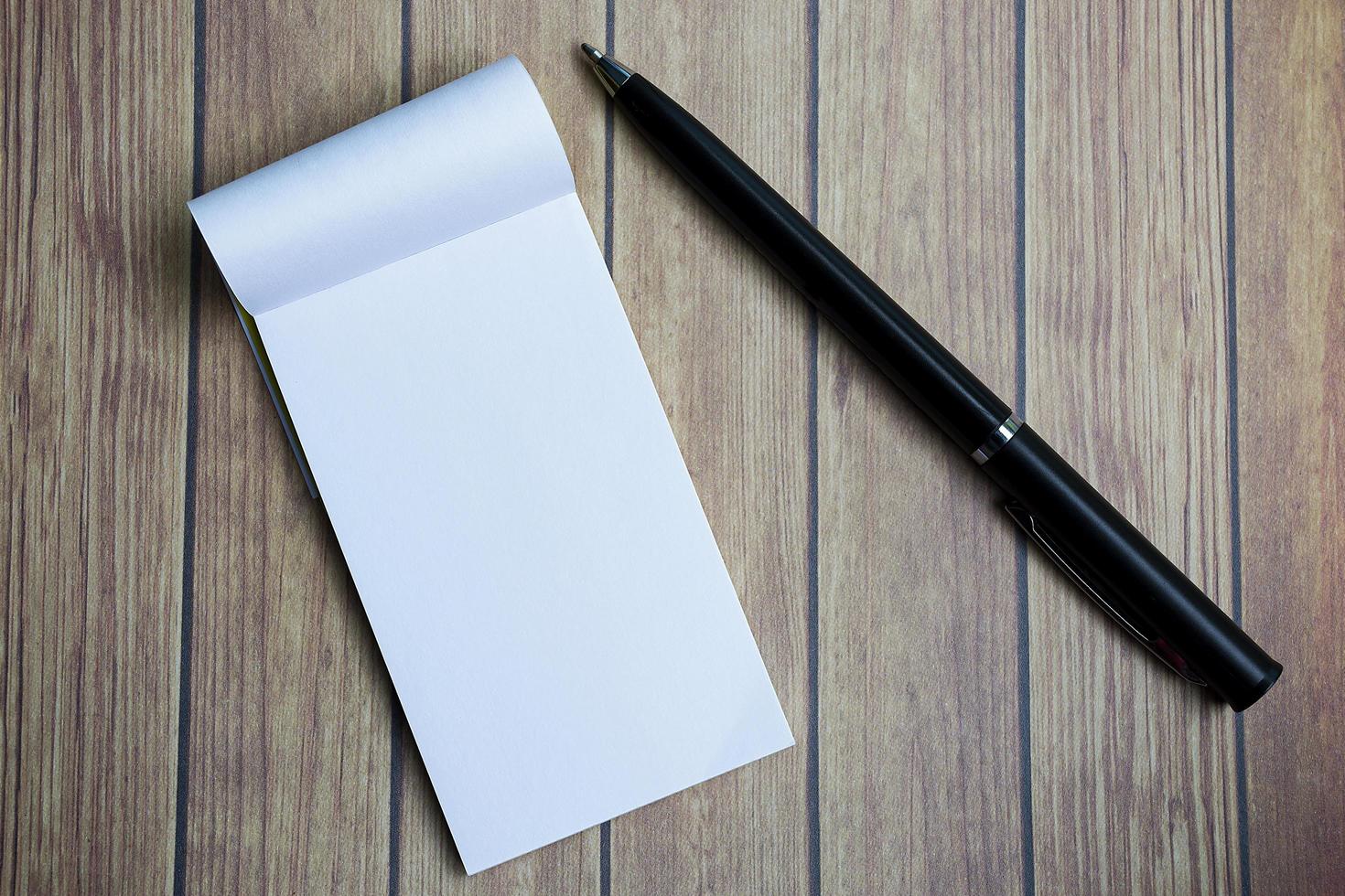 bloc-notes avec un stylo sur un bureau en bois. directement au-dessus. mise à plat. photo