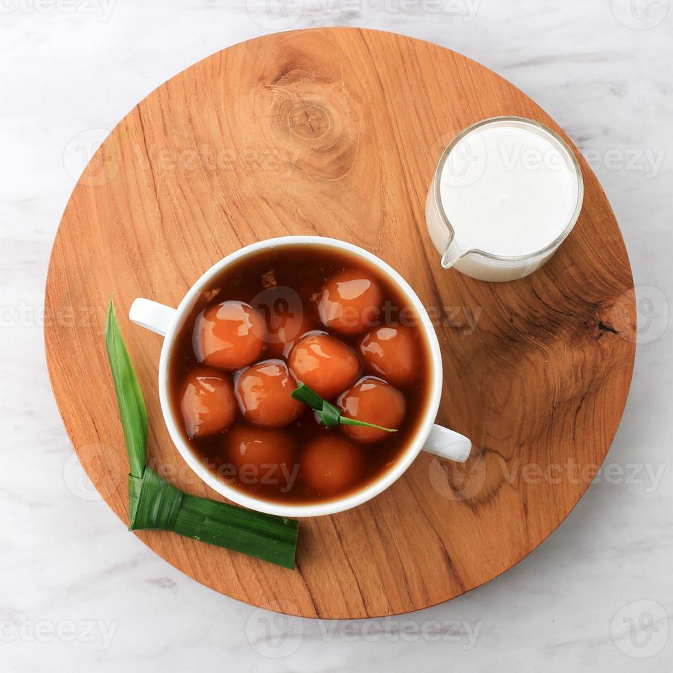 kolak biji salak ou bouillie de patate douce dans un bol blanc sur fond blanc, à base de patate douce, farine de sagou, cassonade et lait de coco. c'est fait pour le takjil ou le dessert photo