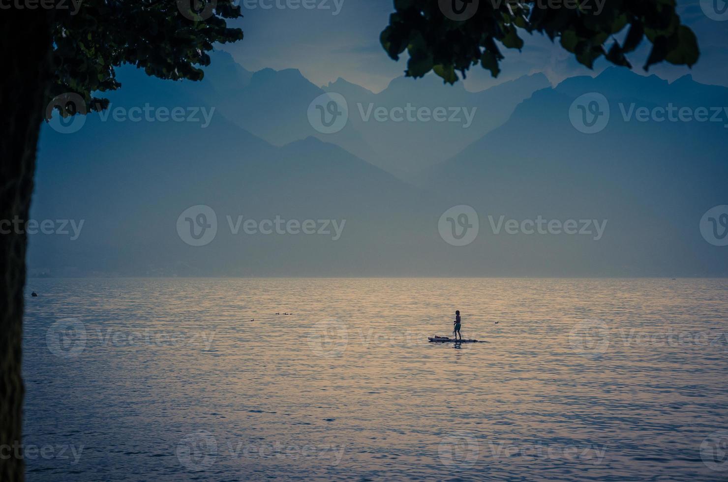 Homme sur une planche de surf avec pagaie sur le lac Léman, Suisse photo