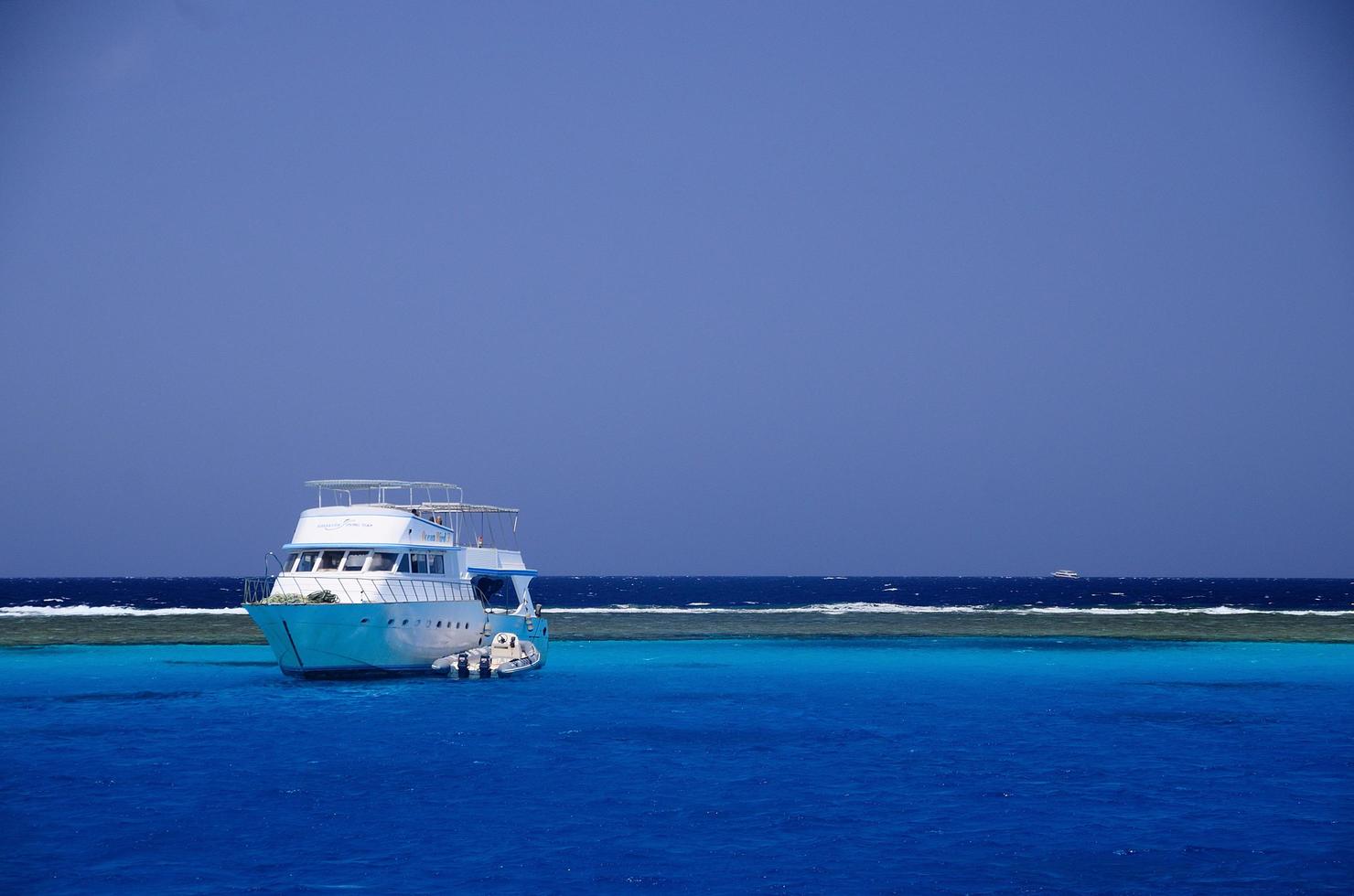 navire sur récif de corail dans la mer d'un bleu profond photo