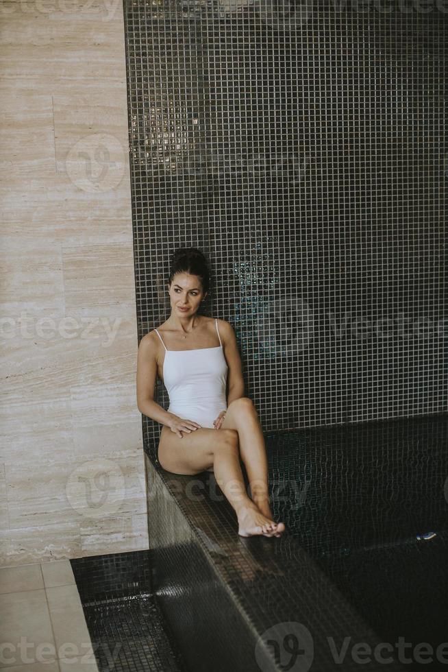 jeune femme se reposant au bord de la piscine intérieure photo