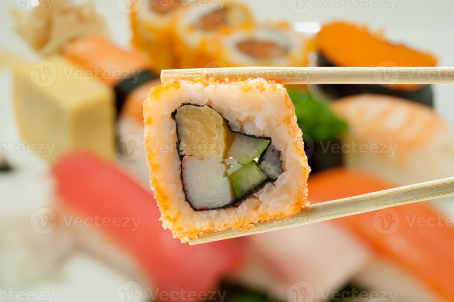 sushi dans des baguettes avec des sushis flous sur un fond de plaque photo