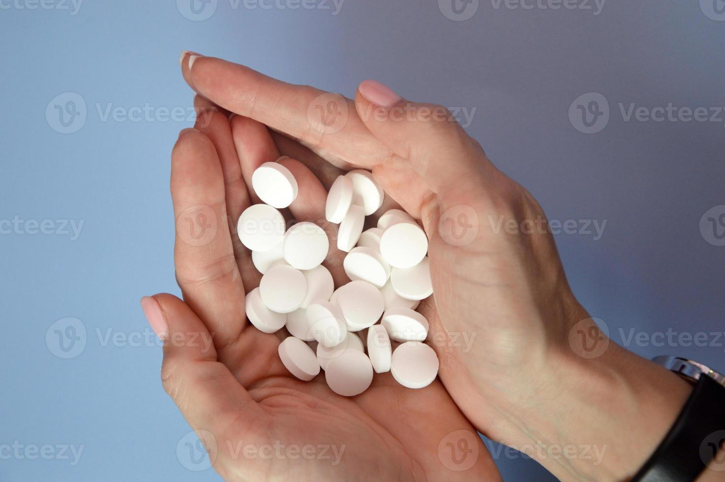 pilules blanches dans les paumes. poignée de médicaments à la main. traitement, soins de santé, médecine, vitamines, médicaments. photo