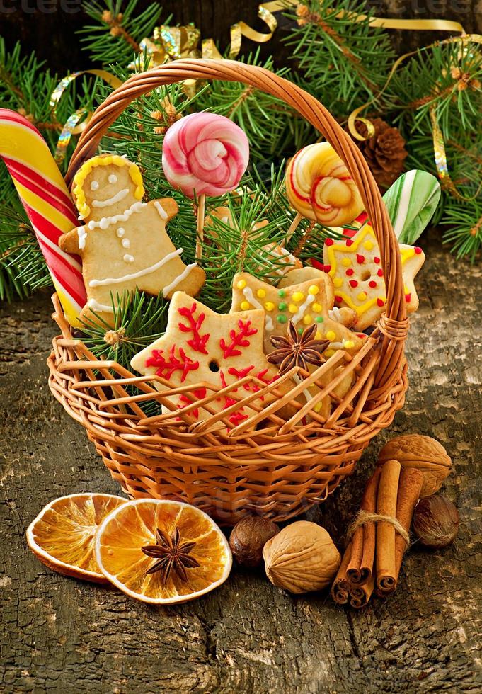 Biscuits de pain d'épice de noël et sucettes dans un panier sur fond de bois ancien photo