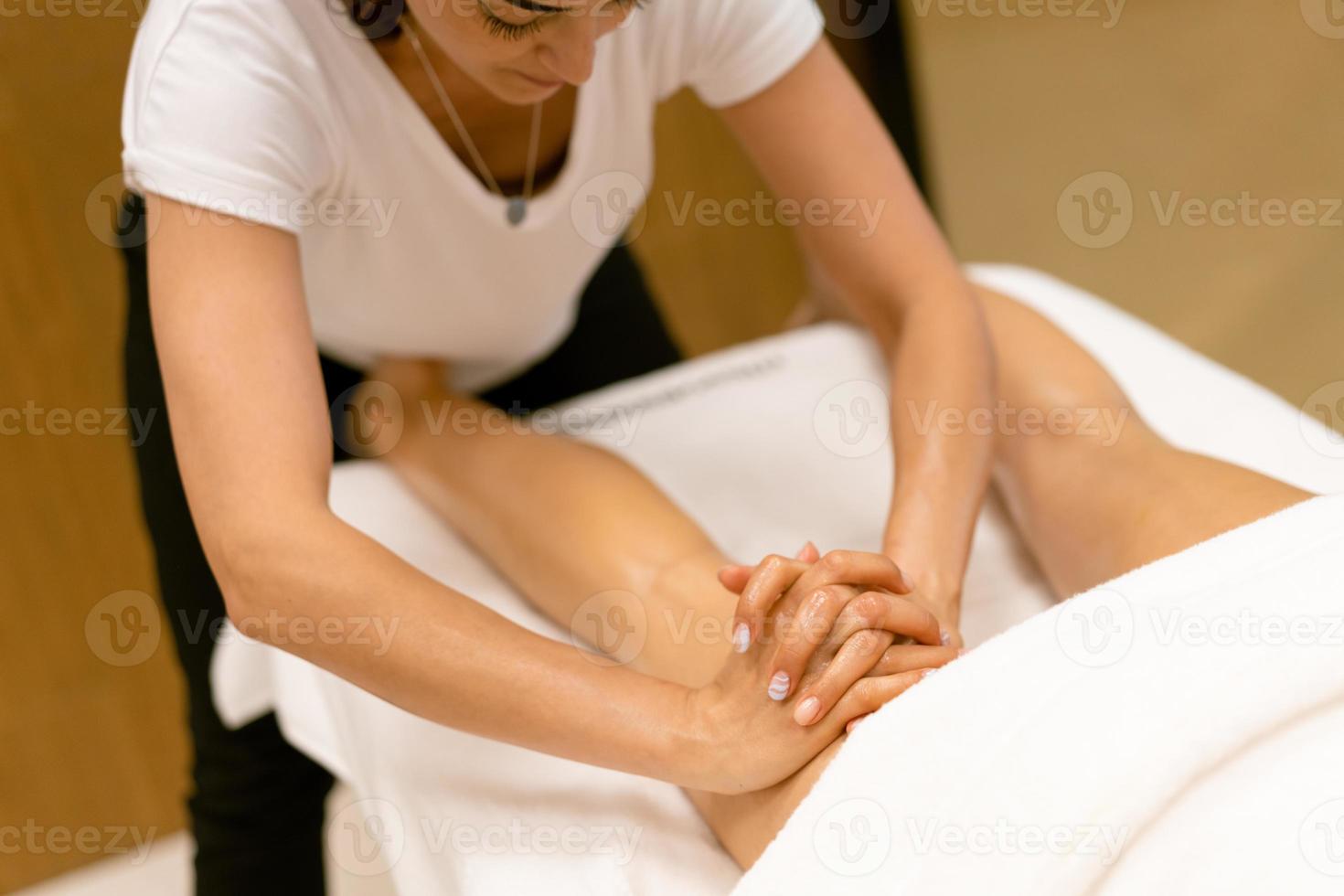 professionnel de salon de beauté versant de l'huile d'une bougie de massage sur le dos de son patient. photo