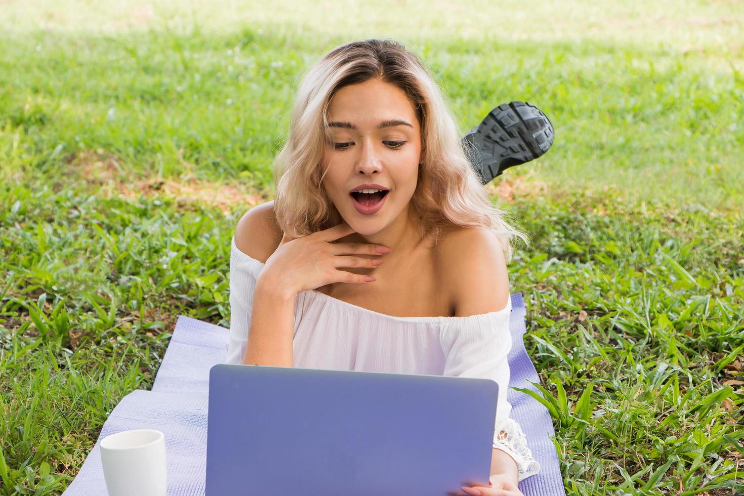 belle femme sur les médias sociaux en ligne avec un ordinateur portable en plein air dans un parc photo