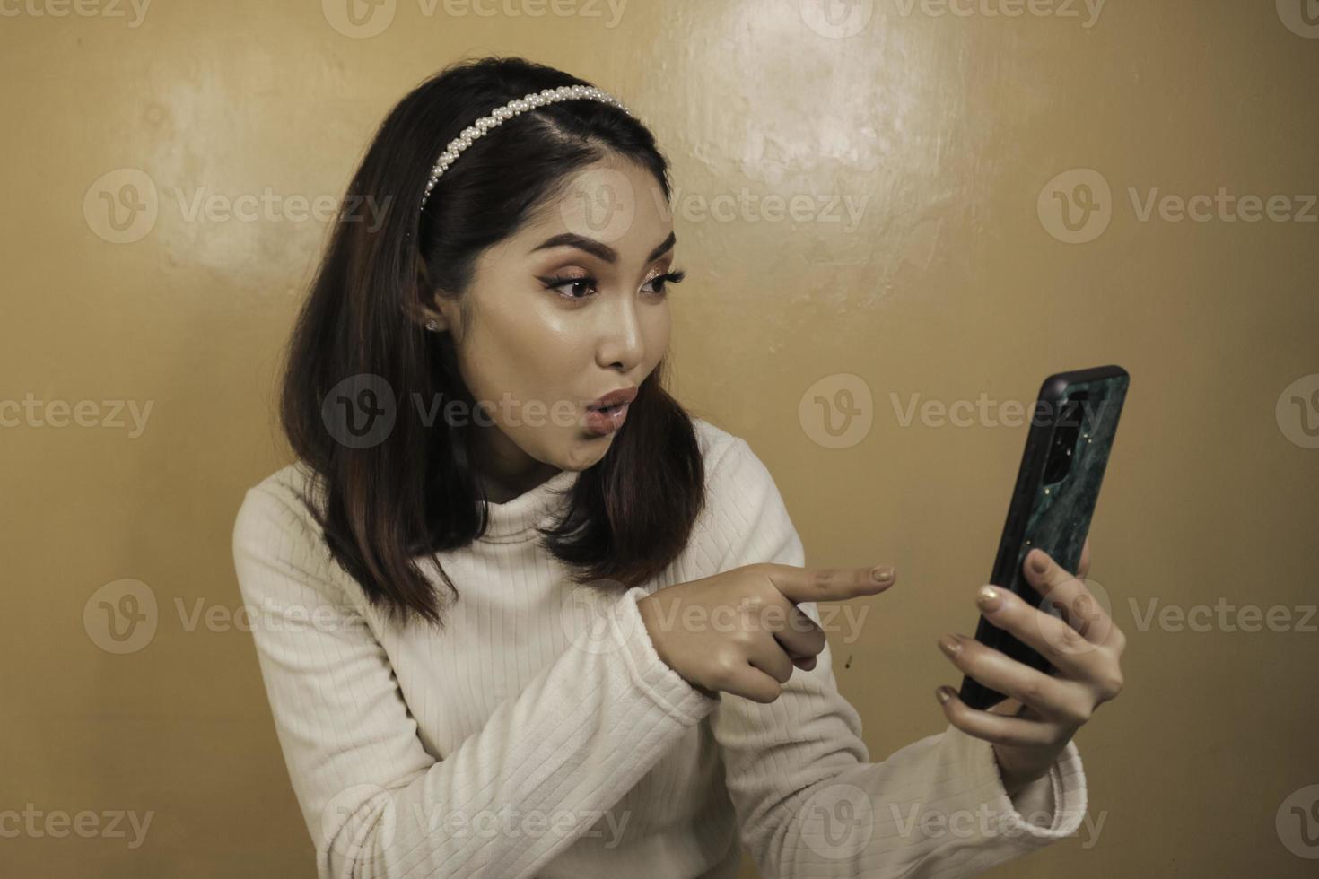 belle fille asiatique est choquée dans le smartphone avec une chemise blanche photo