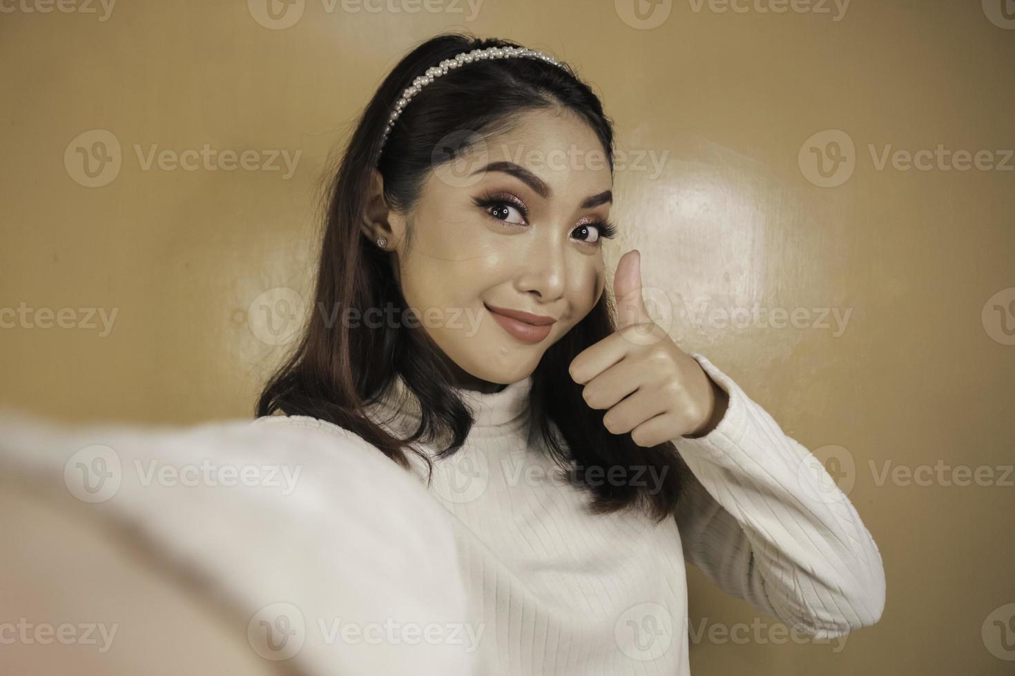jeune femme asiatique est selfie avec un visage souriant heureux et signe ok près de la bouche regarde la caméra photo