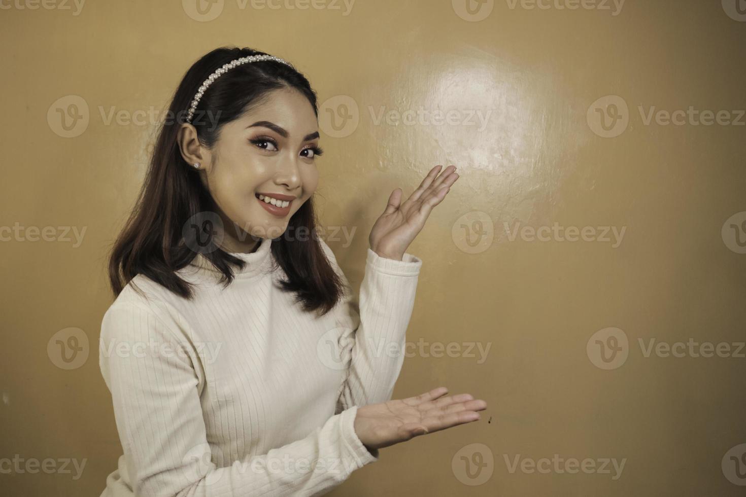 visage heureux et souriant avec le sourire d'une jeune fille asiatique avec un point de main sur un espace vide. photo
